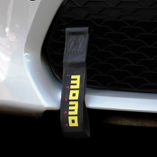A black momo tow strap installed on a white car's front grille