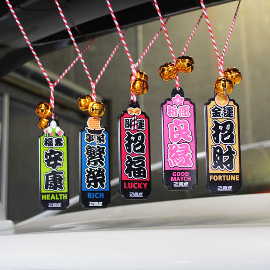 Five Japanese lucky charm with different meanings and colours hung in a white car's spoiler