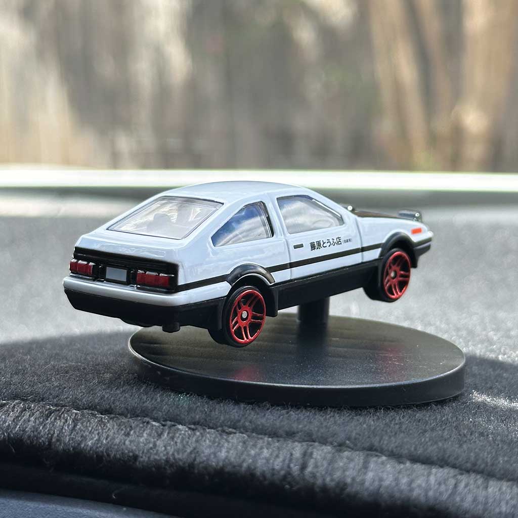 An AE86 car model drifter installed on a dashboard with its tail facing front