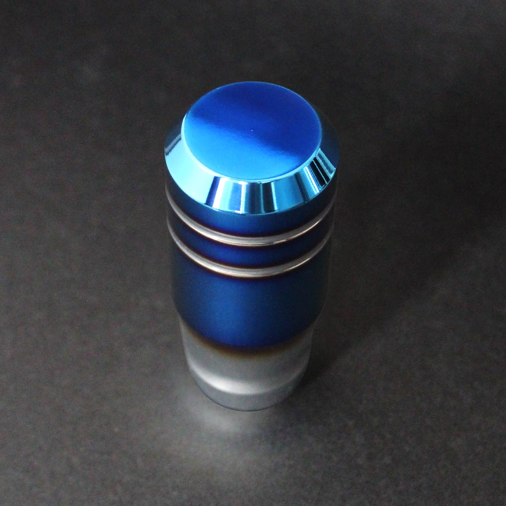 The burnt blue shift knob for auto cars is standing upright on a dark grey background