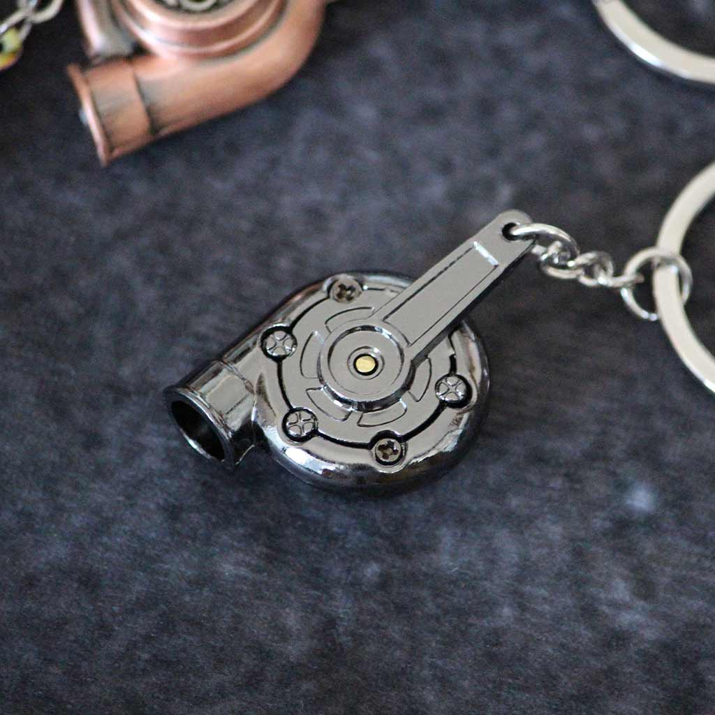 The back of a black turbo keychain, showing five mini screws