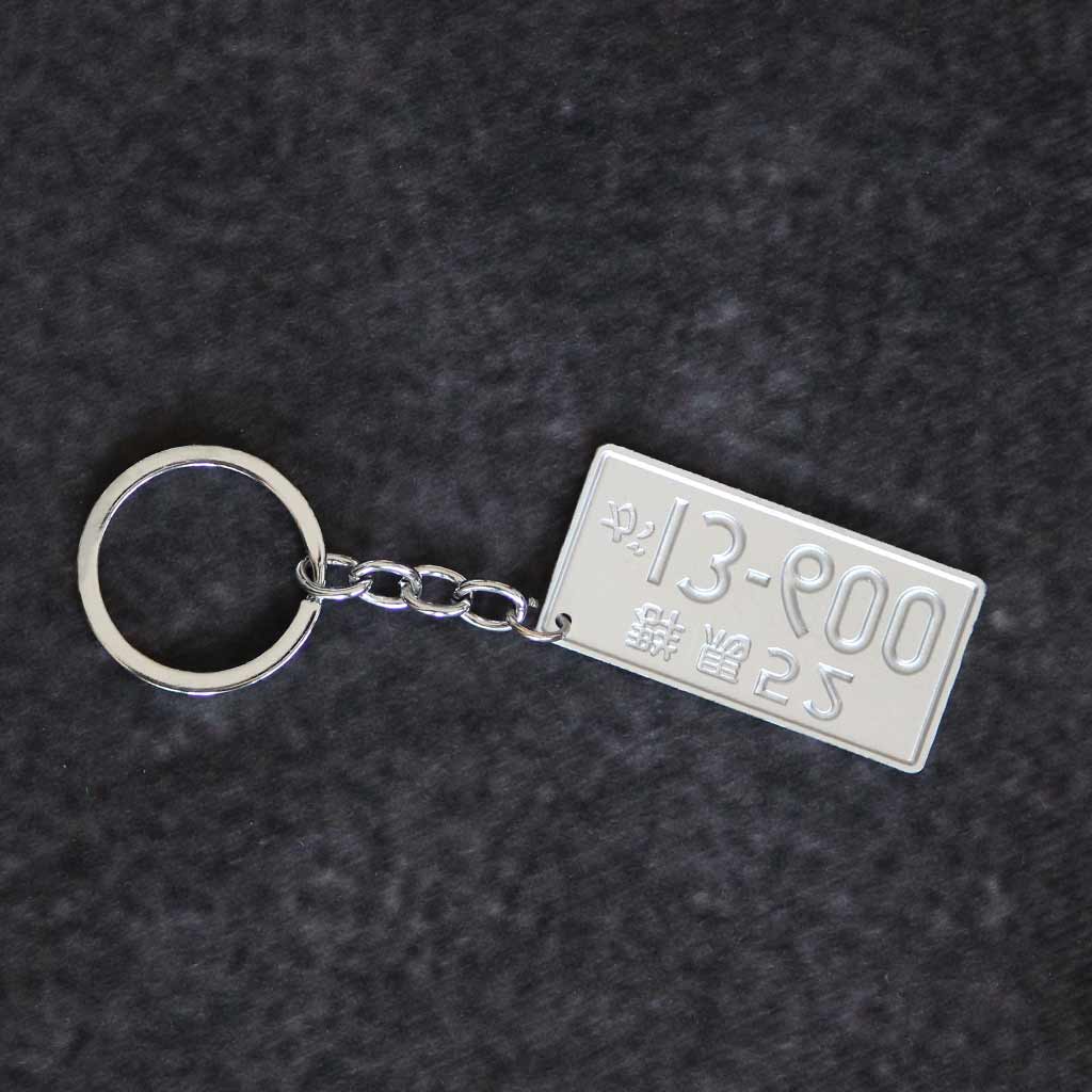 The back of the Initial D number plate keychain on a grey background