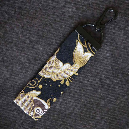 A black koi fish wafu keychain on a grey background