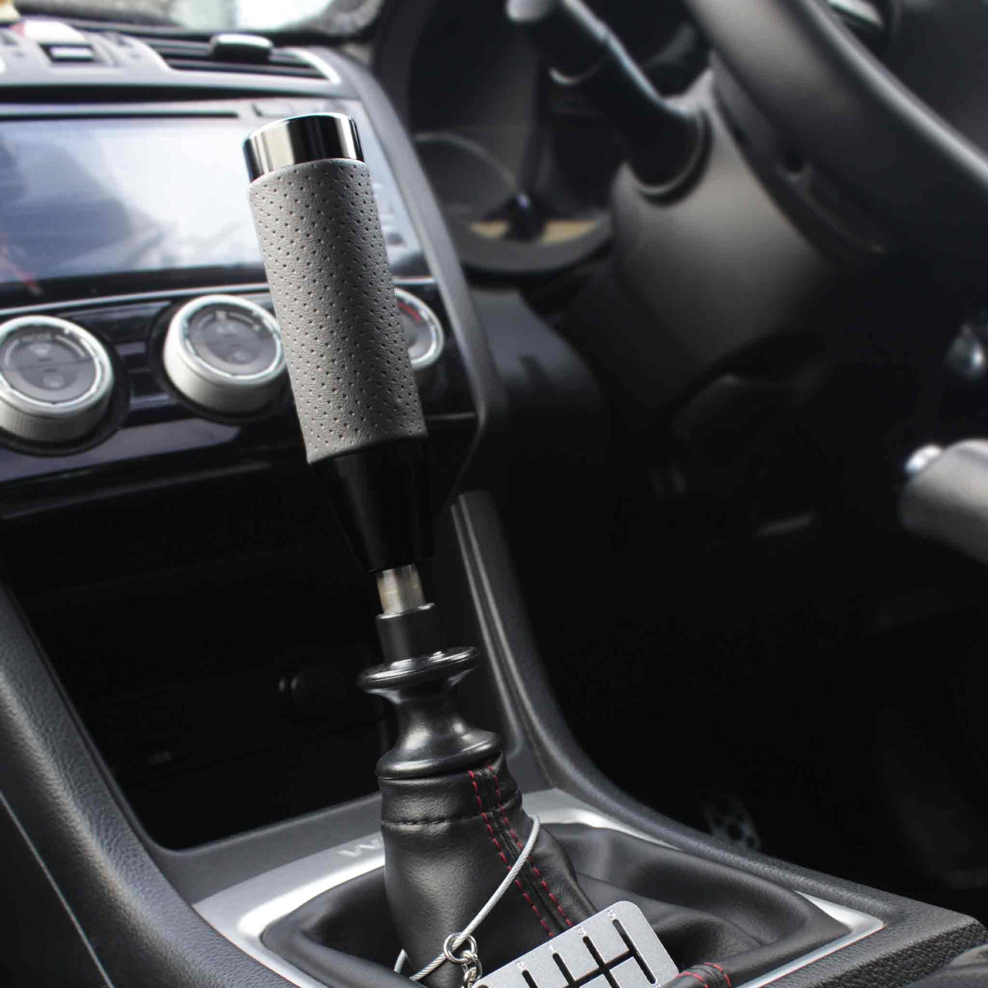 A black leather grip shift knob is installed on a manual WRX, and a six-speed dog-tag is hanging around the shift boot