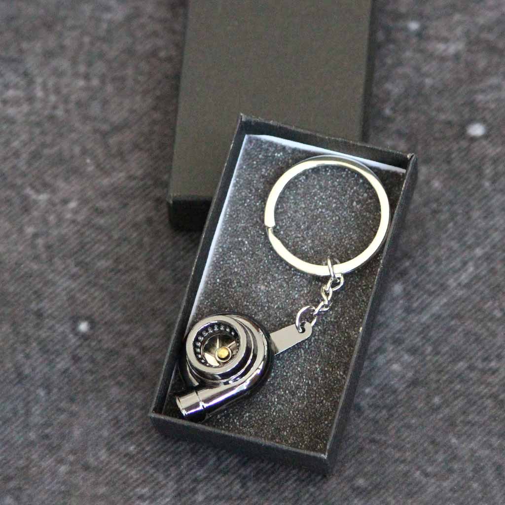 A black turbo keychain in a gift box on a dark grey background