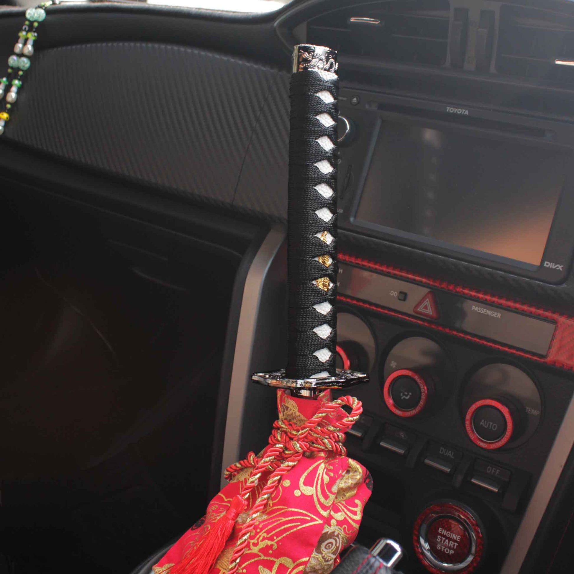 A black and white katana shift knob is installed on an auto Toyota 86, with a red koi fish shift boot cover underneath