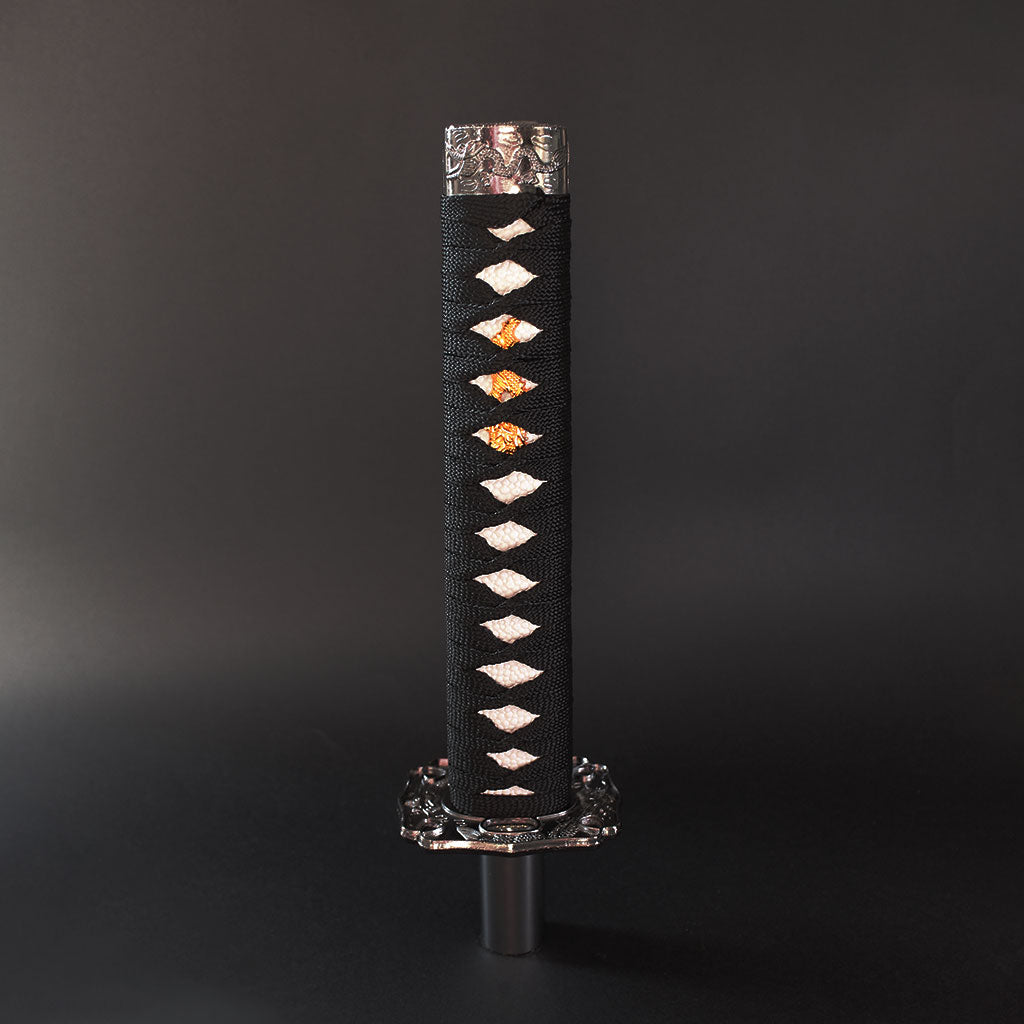 A black and white katana shift knob is standing upright on a dark grey background