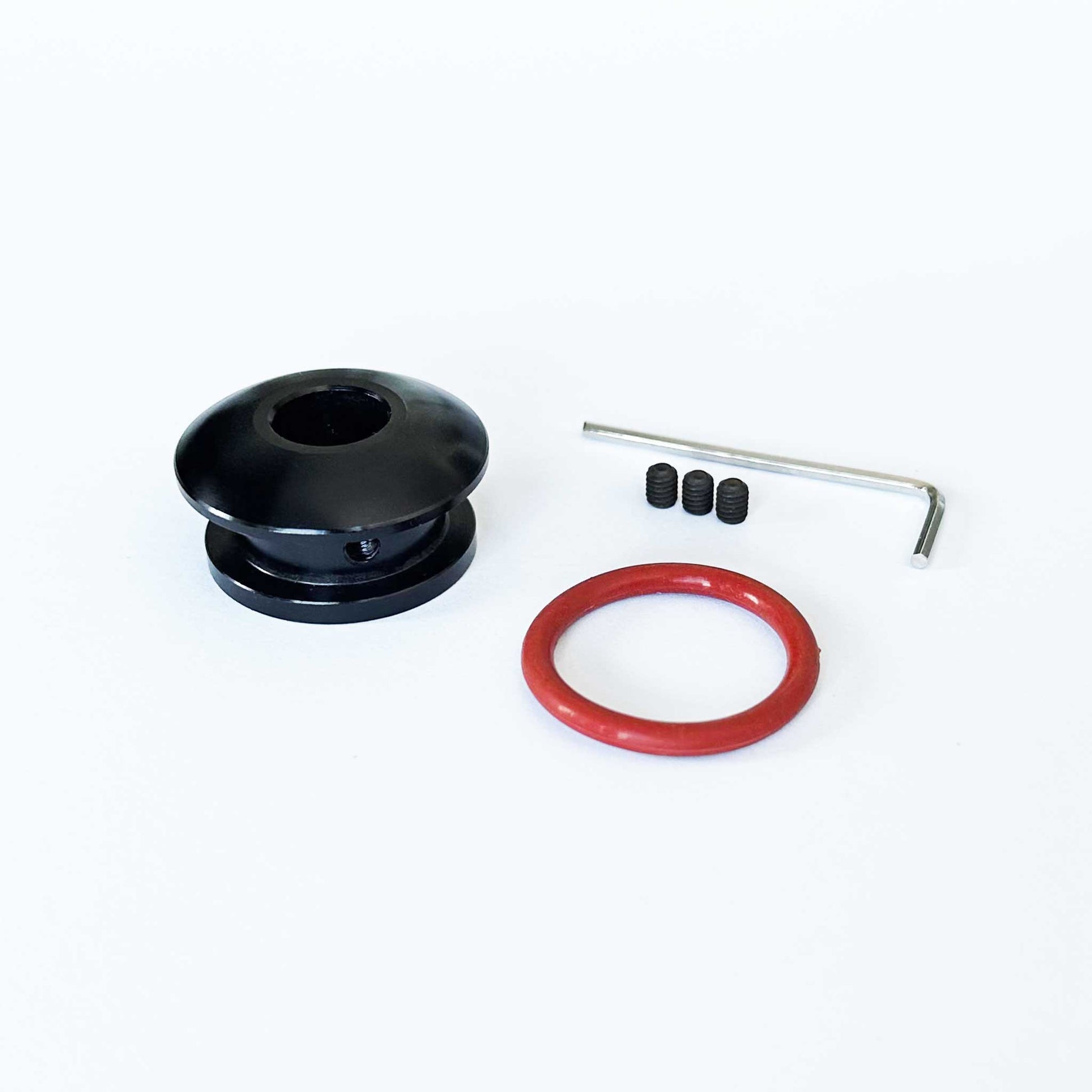 A black non-threaded boot retainer is standing upright on a white background with installation tools beside it