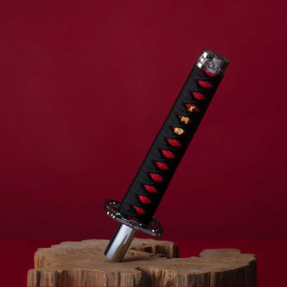 A black katana shift knob is standing on a wooden object on a red background