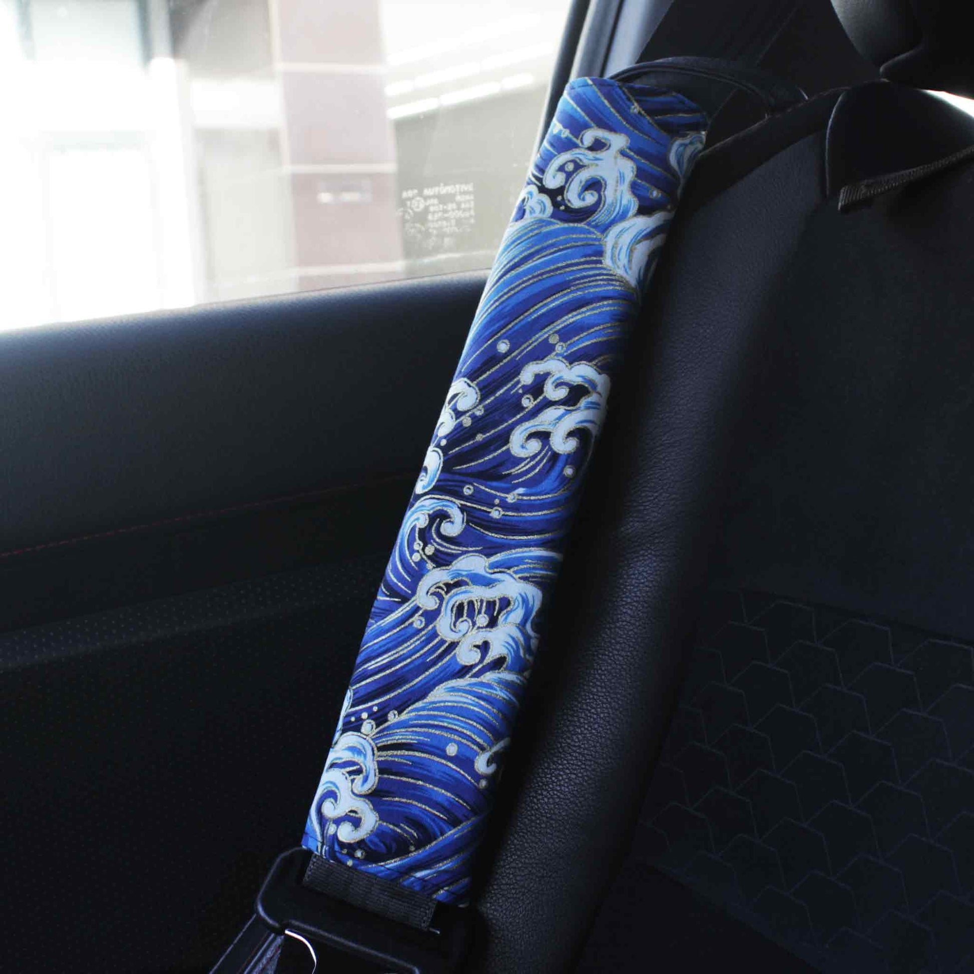A seat belt cover with blue great waves pattern installed on a Toyota 86's seat belt