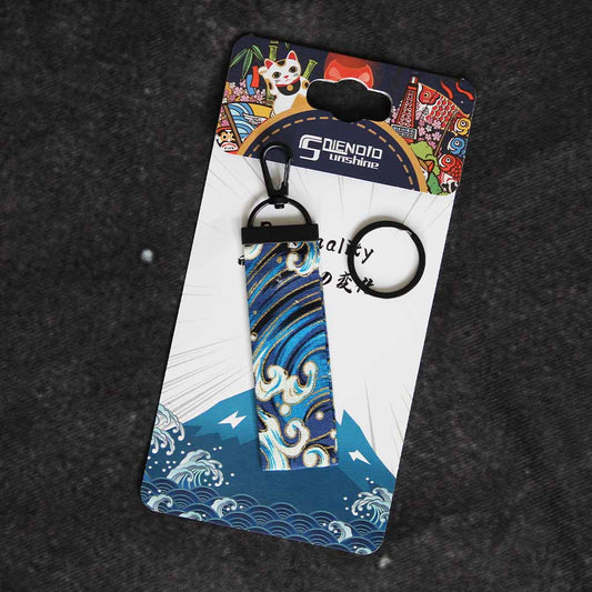 A blue wave wafu keychain placed on a Japanese style packaging on a grey background