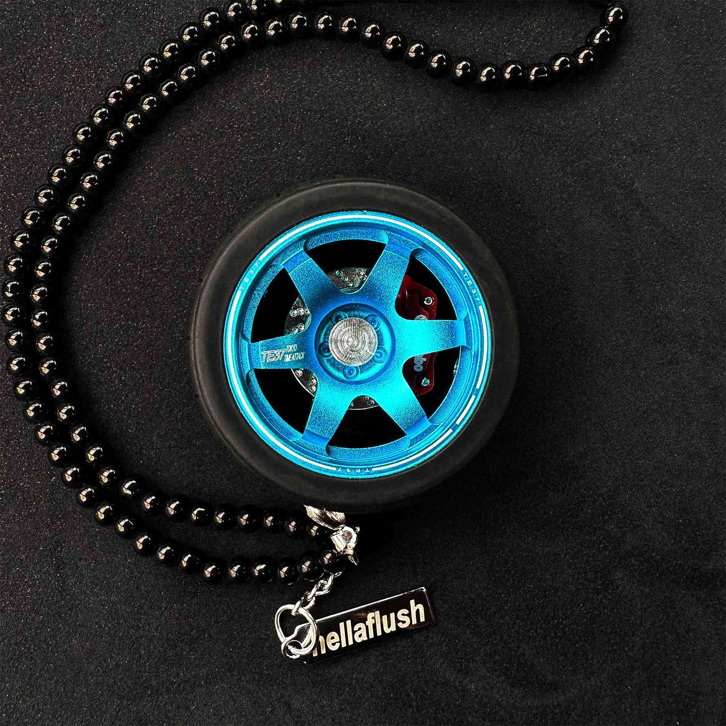 A blue TE37 air-freshener is flat laid on a black background