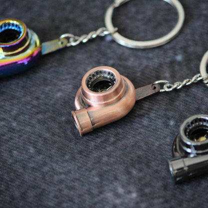 Close-up of a brass turbo keychain with a black and a rainbow ones on both sides