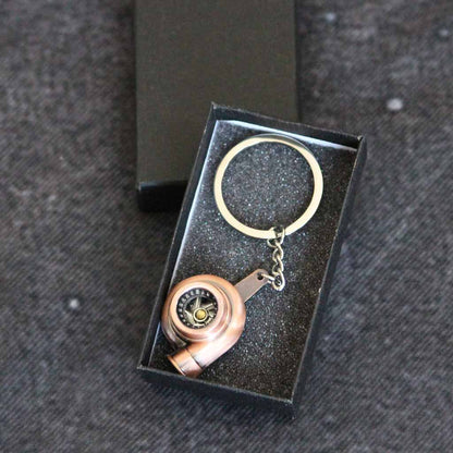 A bronze turbo keychain in a gift box on a dark grey background