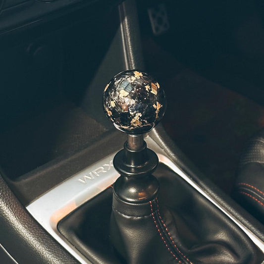 A black and gold spherical carbon fibre shift knob installed in a 6-speed manual 2015 subaru wrx