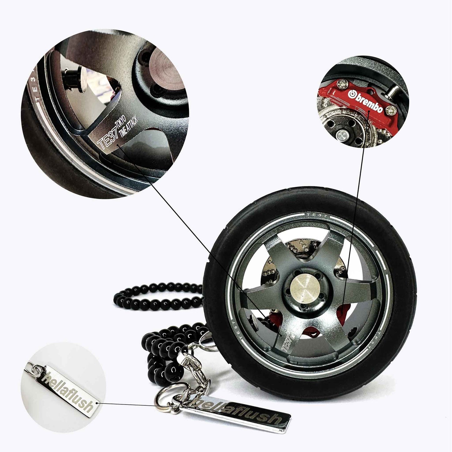 A grey TE37 wheel air-freshener standing on a white floor with bubbles around showcasing its details such as brembo calliper, the Hella Flush dog tag, and the writings on the spoke