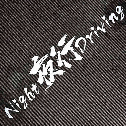 A white Night Driving car vinyl decal flat laid on carpet