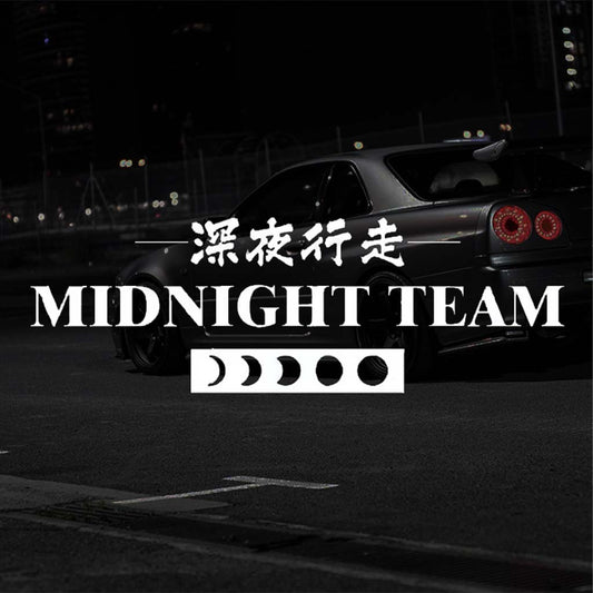 A white Midnight Team car vinyl decal horizontally placed pointing to the screen with a darkened Skyline R34 at the back