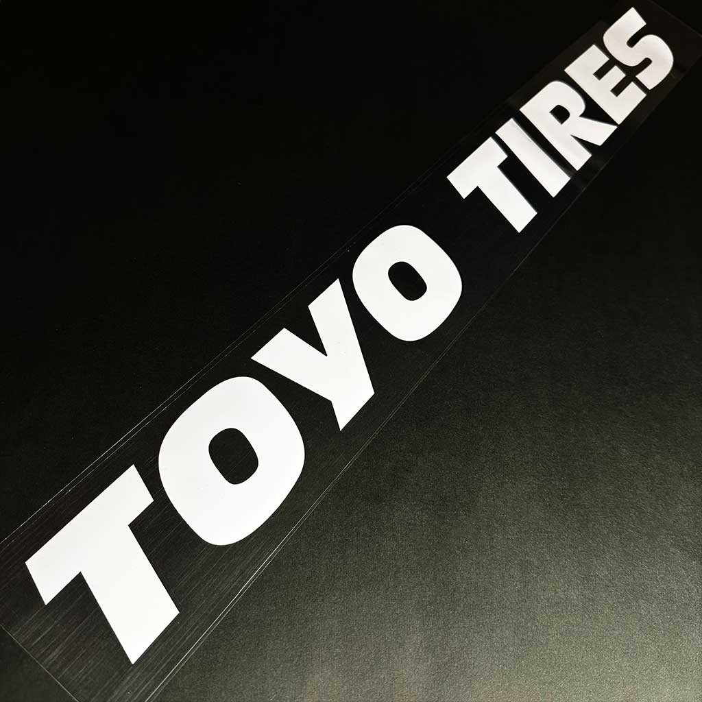 A TOYO TIRES car vinyl decal is placed on a black background