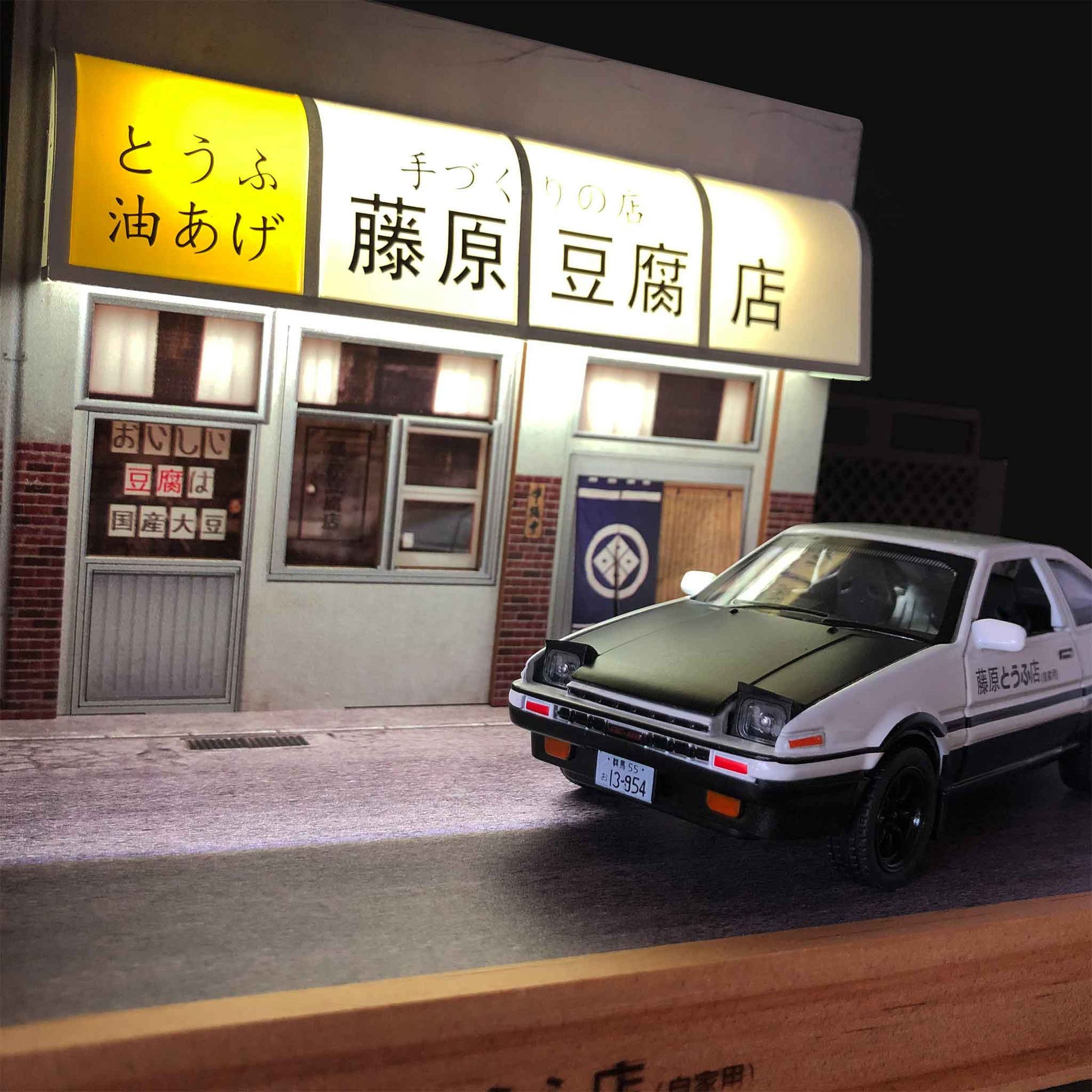 An AE86 car model in a Fujiwara tofu shop diorama with LED light on