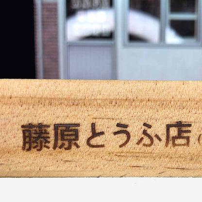 A wooden base with Fujiwara Tofu Shop writings