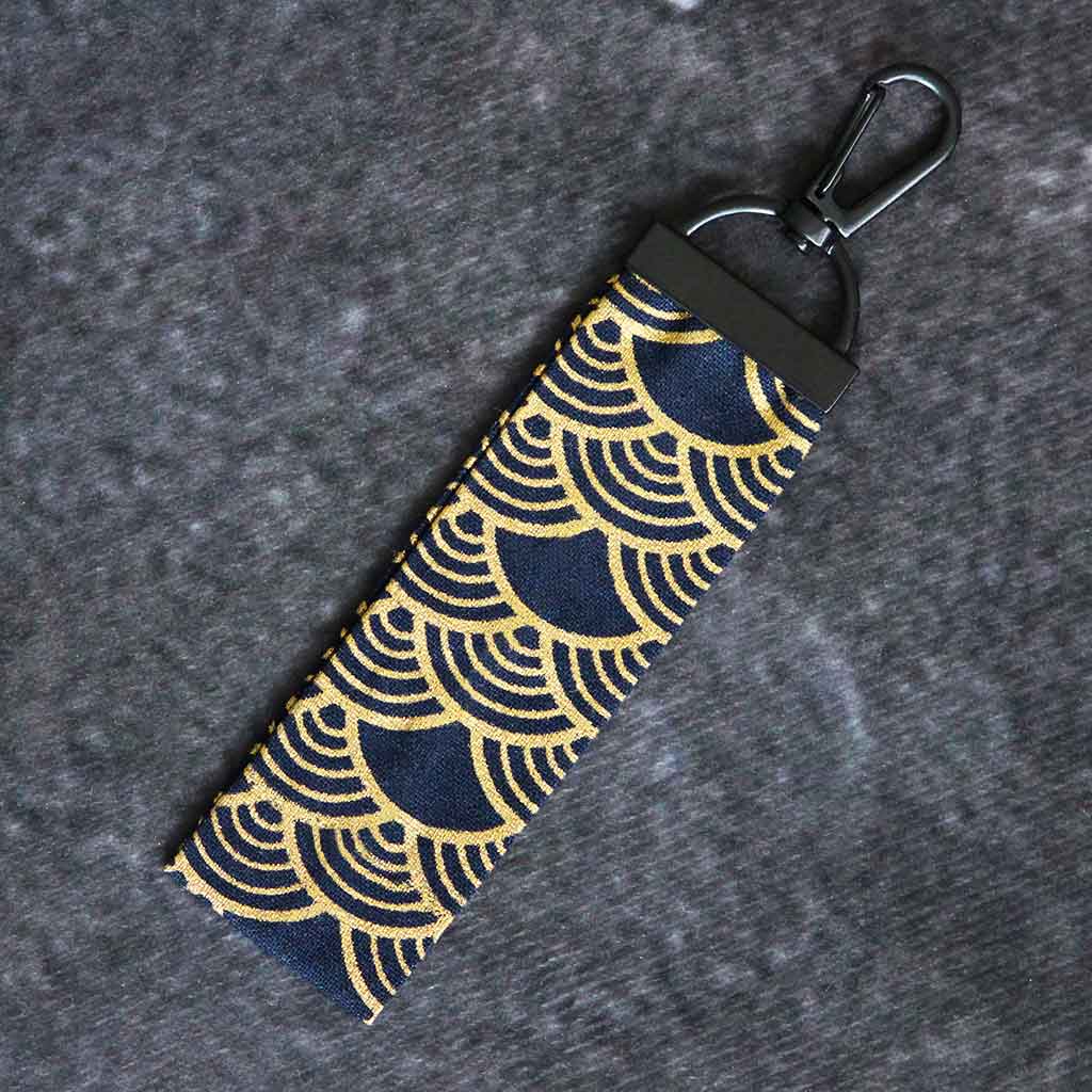 A gold wave keychain on a grey background