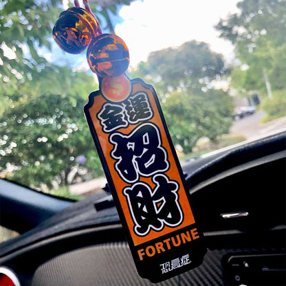 A yellow Japanese charm meaning 'good fortune' hung on a car's rearview mirror