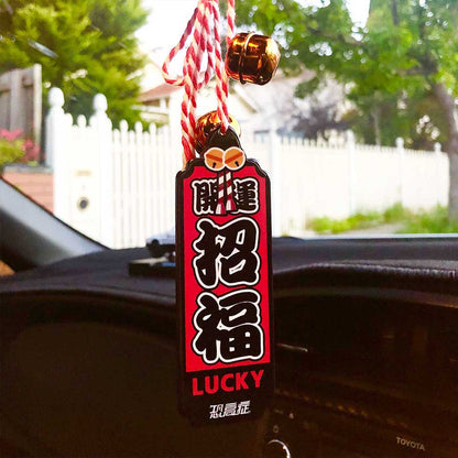 A red Japanese charm meaning 'good luck' hung on a car's rearview mirror