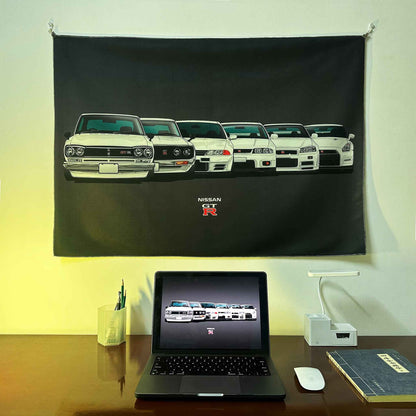 A GTR evolution artwork hung on a wall, with a laptop showing the same photo as the wall poster underneath, lit by red spotlight