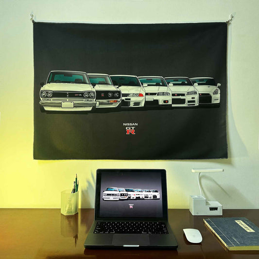 A GTR evolution artwork hung on a wall, with a laptop showing the same photo as the wall poster underneath, lit by red spotlight