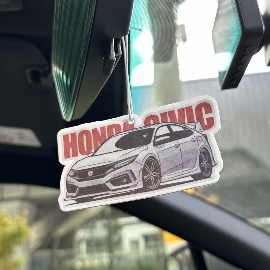 A Honda civic air freshener hung on a rear mirror in a car and the background is blurred