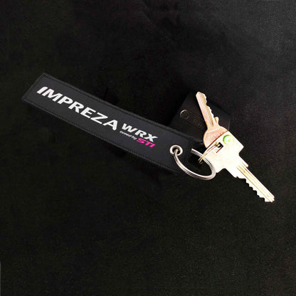 An sti jet tag holding two door keys on a black background
