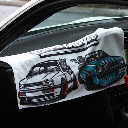 A car towel featuring two European vintage cars and the white writing 'Euro Magic' is placed on a car's centre console