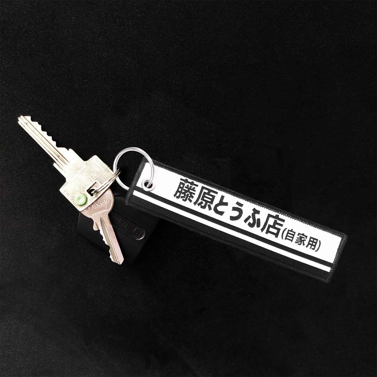 A tofu shop jet tag holding two keys on a black background