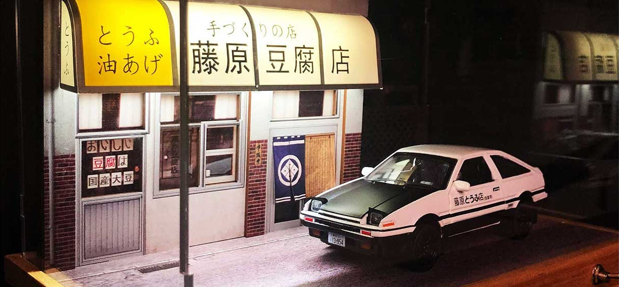 An Initial-D fujiwara tofu shop diorama with lights on and an AE86 car model in front of it