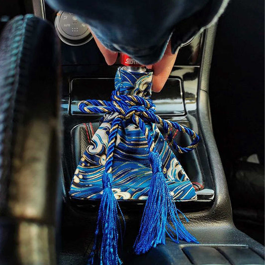 A blue waves shift stick cover installed on a car's shift boot, and the shift knob is held by a hand