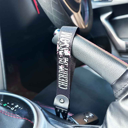 A cherry blossom keychain hung on a JDM car's handbrake