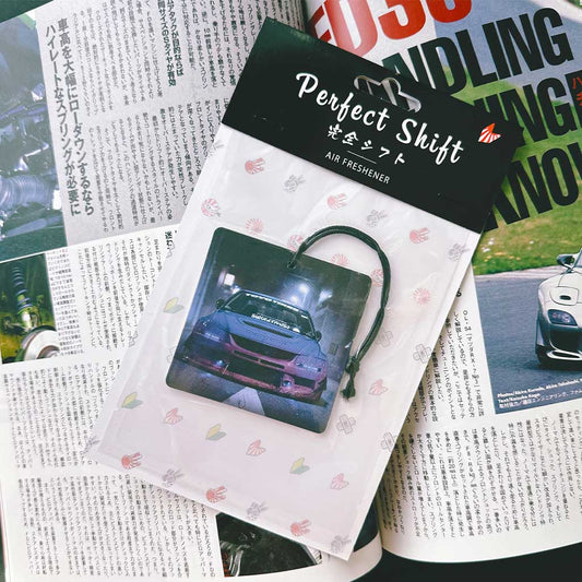A JDM car air freshener themed mitsubishi evo 8 flat laid on a Japanese magazine