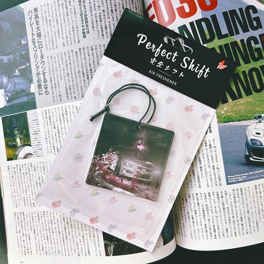 A JDM car air freshener themed Mitsubishi evo 9 flat laid on a Japanese magazine