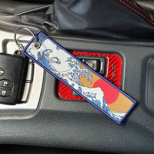 A Japanese style keychain with great wave pattern placed on a Toyota 86's center console 