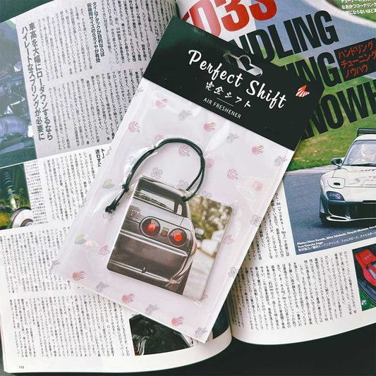 A JDM car air freshener themed Nissan GTR32 flat laid on a Japanese magazine