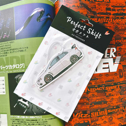 A JDM car air freshener themed Mitsubishi Lancer flat laid on a Japanese magazine