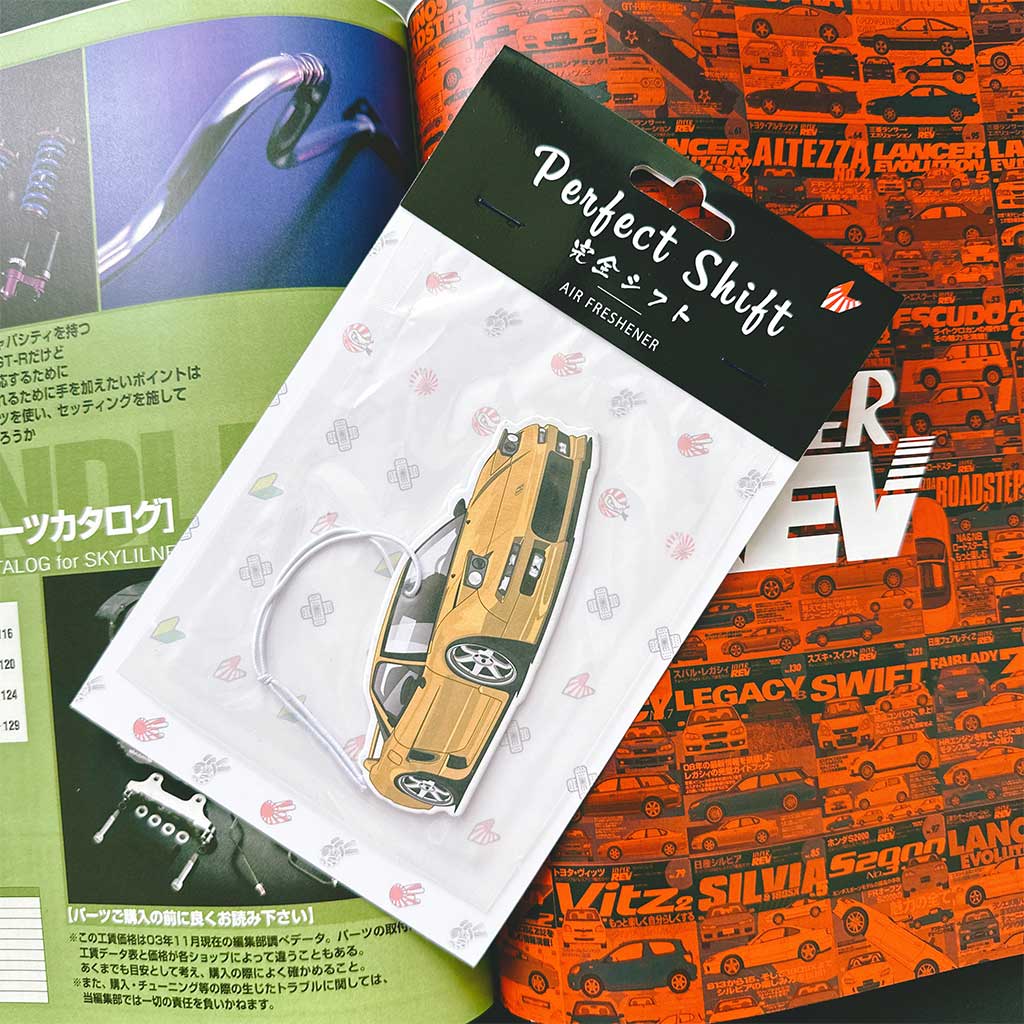 A JDM car air freshener themed Honda NSX flat laid on a Japanese magazine