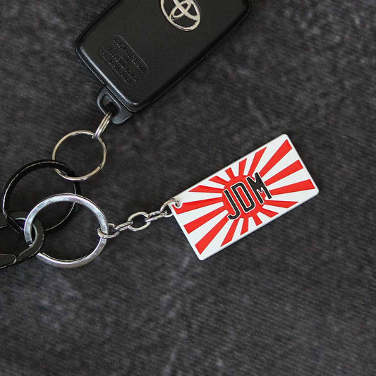 A JDM keychain featuring a rising sun holding a Toyota car key on a dark grey background