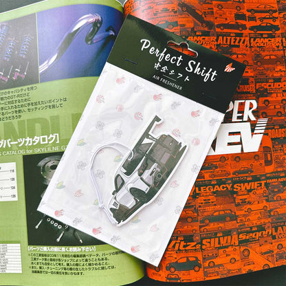 A JDM car air freshener themed wide-bodied RX7 flat laid on a Japanese magazine