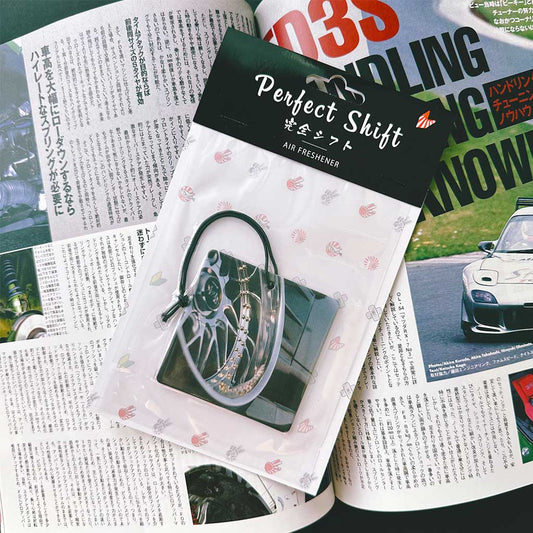 A JDM car air freshener themed vintage wheels flat laid on a Japanese magazine