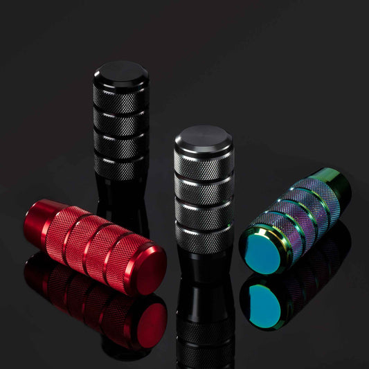 Four knurled grip shift knobs in different colours placed on a reflective object