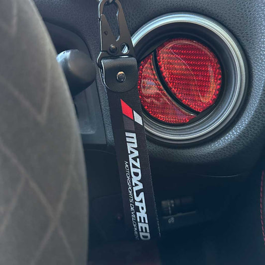 A Mazda keychain with 'Mazda Speed' characters hung in a Mazda car