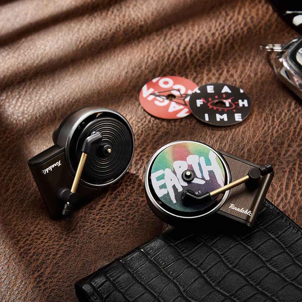 Two mini record player air fresheners are placed on a luxurious leather, with two fragrance discs behind them