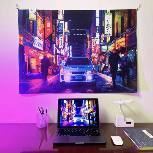 A Mitsubishi EVO artwork hung on a wall, with a laptop showing the same photo as the wall poster underneath, lit by purple spotlight